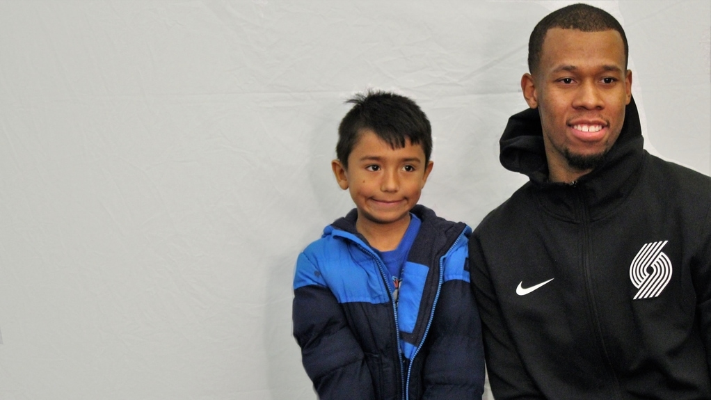 A young boy stands next to Rodney Hood.