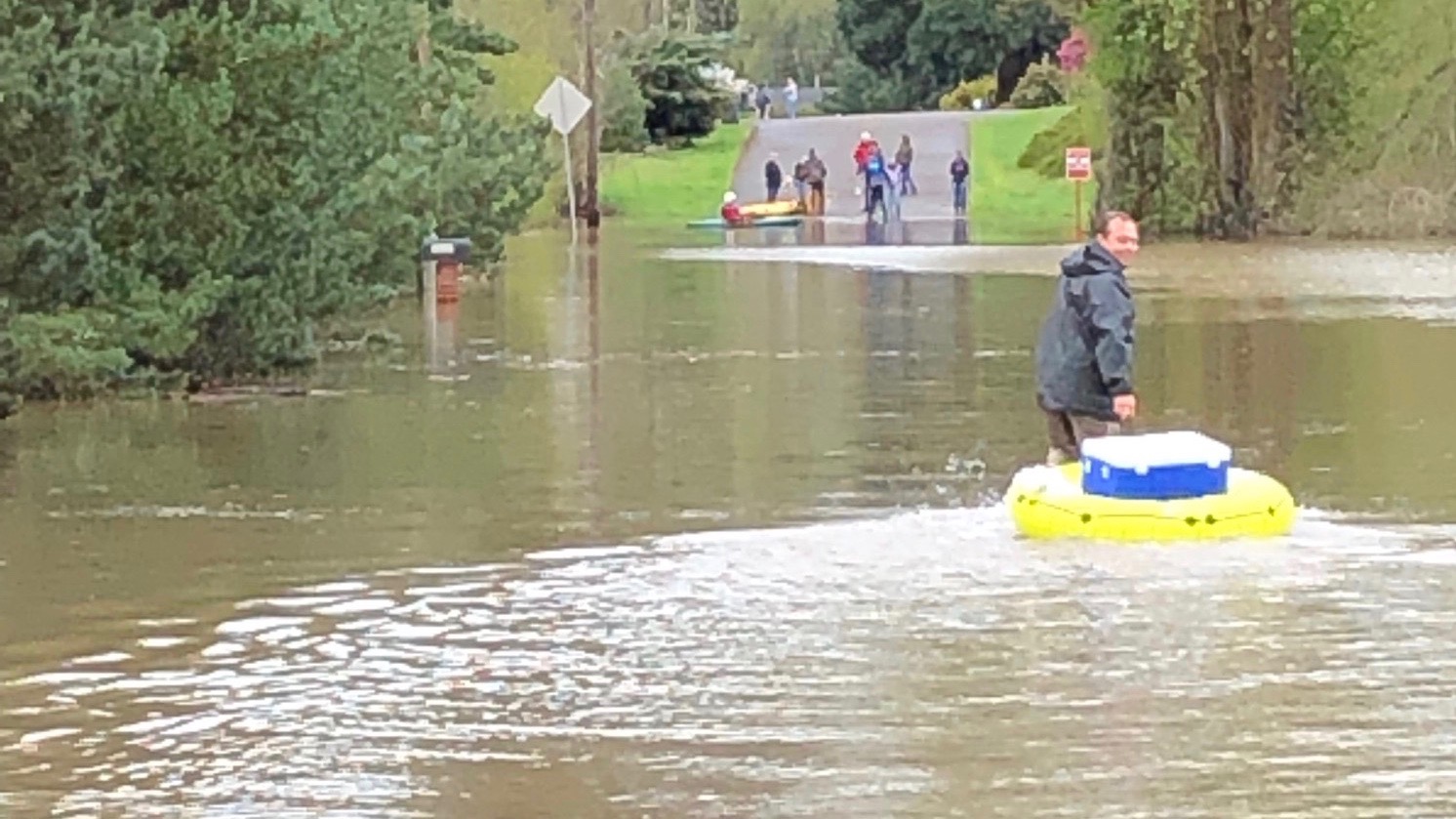 Eder Perez pulls an innertube full of groceries across a flooded road.