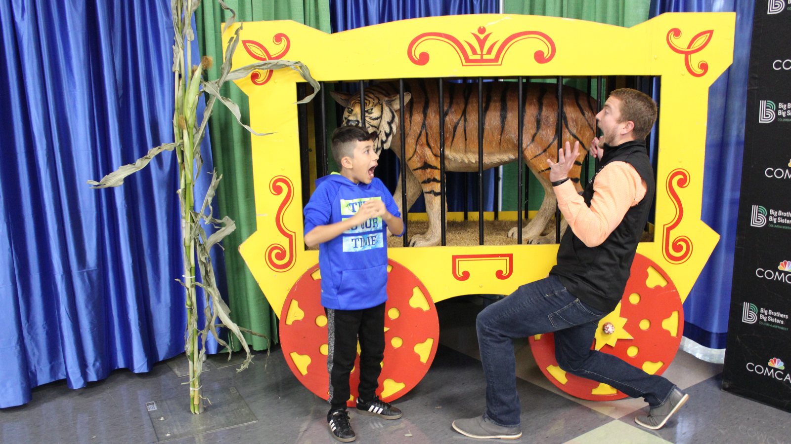 A Big Brother and Little Brother in front of a replica circus car.