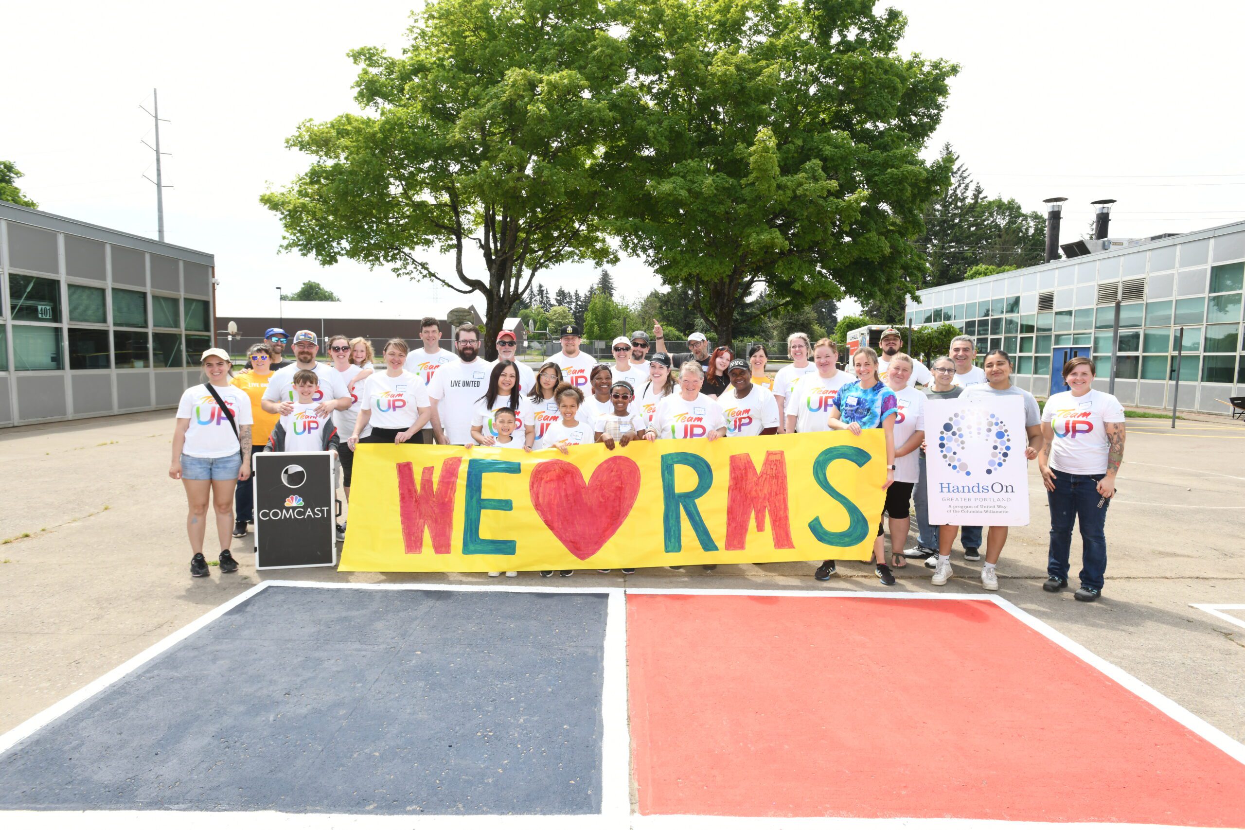 Volunteers pose with a sign which reads we heart RMS.