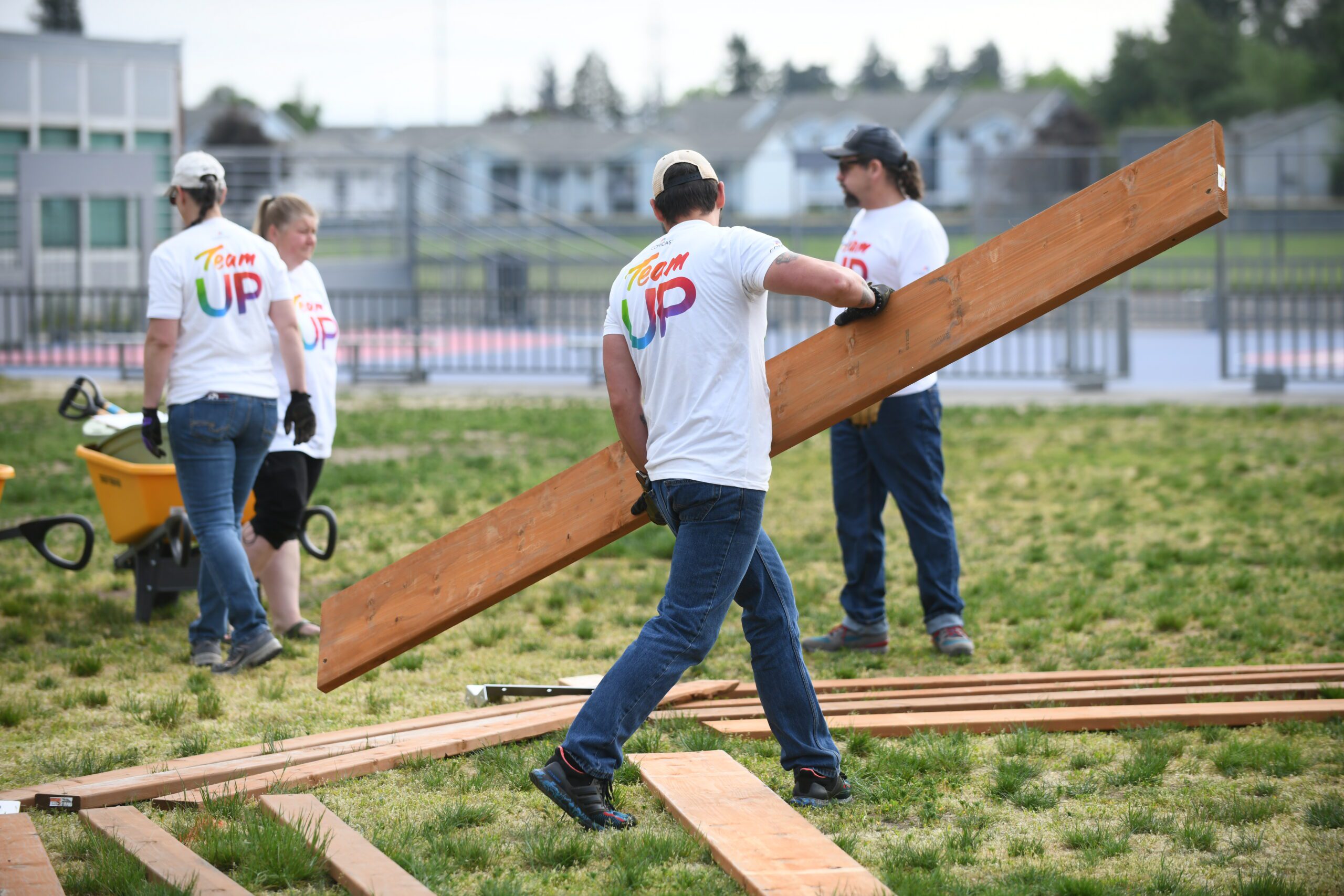 People carrying wood on a lawn.