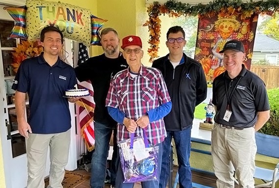 Jerry Lauzon stands on his porch with employees from Comcast. 