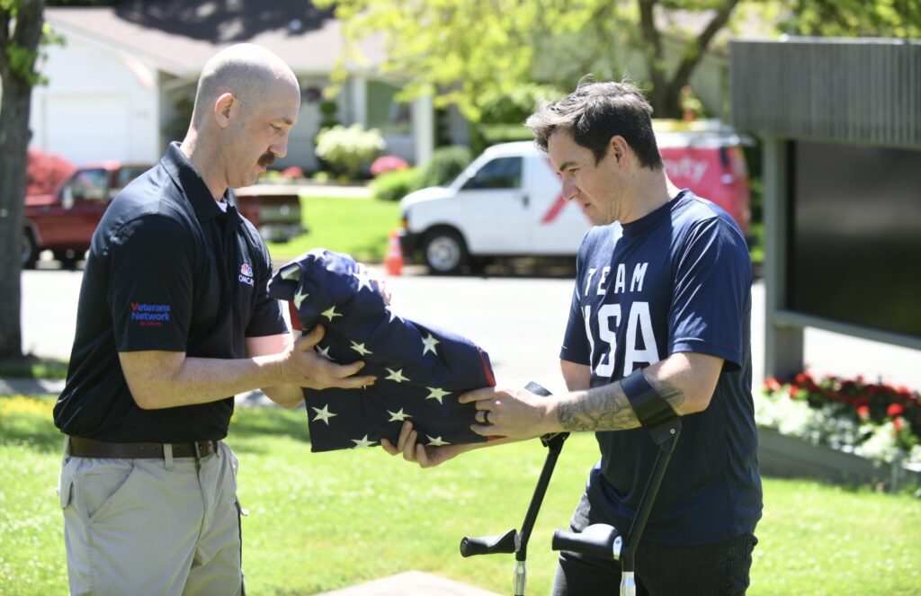 Two men fold an American flag. 